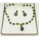 A Tibetan silver and green jade necklace and earrings set with hand carved smiling Buddha head