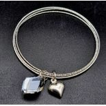 A sterling silver triple bangle with two charms. . Weight: 14.7 g.