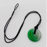 A round shaped jade pendant on cord. Diameter: 32 mm.