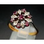 An 18 K white & yellow gold ring with a cluster of rubies and diamonds.