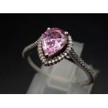 A 9 K white gold ring with a pear shaped pink sapphire and numerous diamonds (0.12 carats). Size: L,