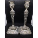 A pair of early George V sterling solid silver mounted candlesticks, each with filled square base