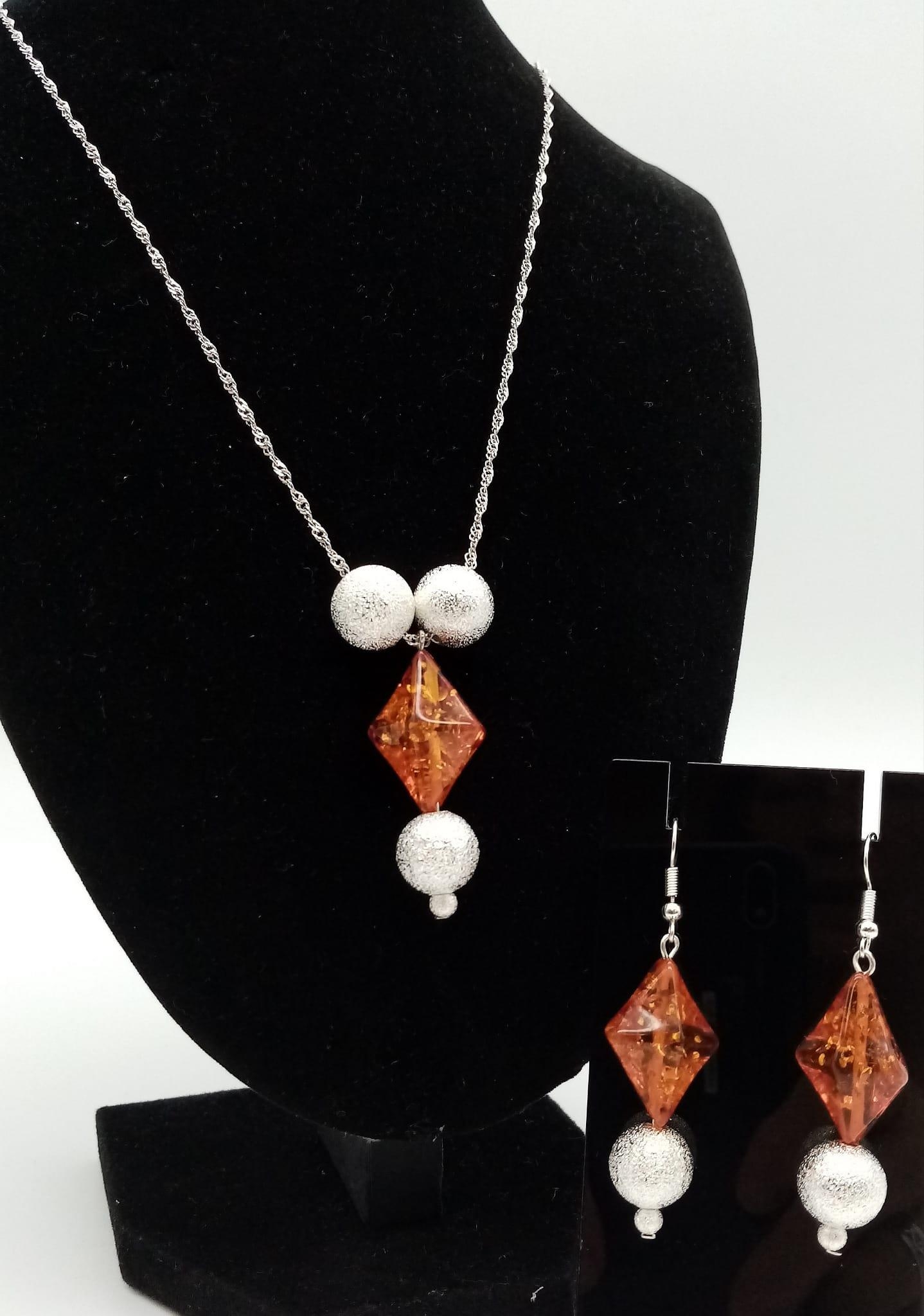 A glamorous sterling silver pendant (with chain) and earrings set with amber resin. Necklace length: