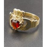 A 9 K yellow gold garnet set Claddagh ring. Size: P, weight: 2.9 g.