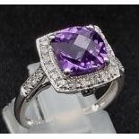 An Eye-Catching 9K White Gold Amethyst and Diamond Ring. Multi-faceted central clean amethyst