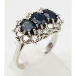 An 18K White Gold Diamond and Sapphire Ring. Three central oval cut sapphires surrounded by