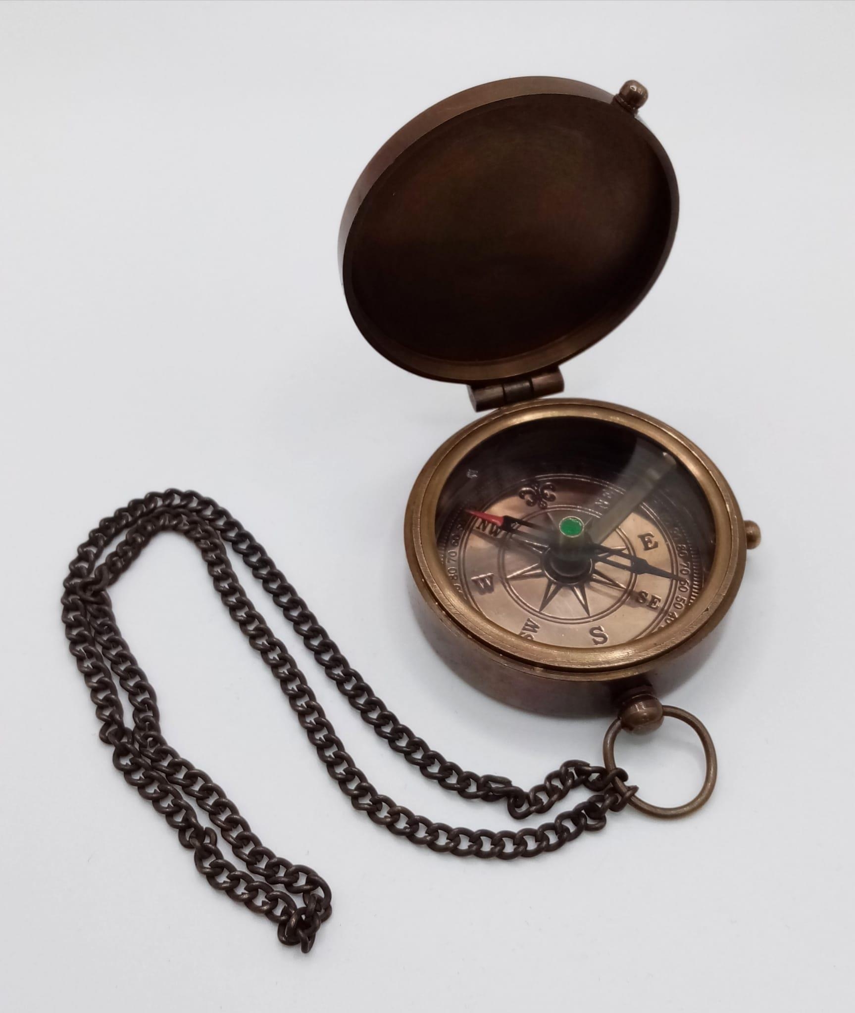 A brass compass with immobiliser, brass chain and inscription BERLIN 1936 in a wooden box with