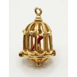 A 9 K yellow gold bird cage charm, which opens to reveal a red enamelled exotic bird. Height: 20 mm,