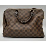 A Louis Vuitton Speedy Checked Canvas Bag. Leather handles. Padlock. Red interior with flap pocket.