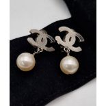 A Pair of Chanel Monogram Pearl Earrings. Comes in a Chanel pouch with box. On white metal. 3cm