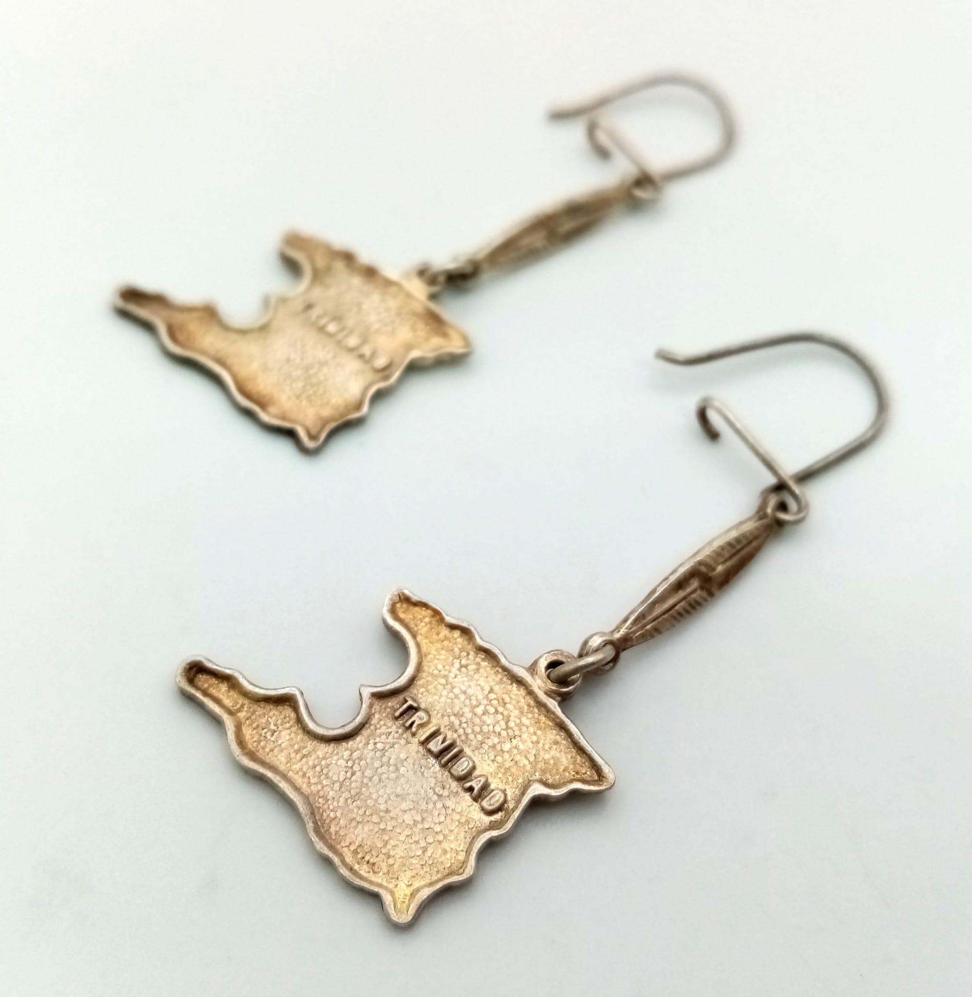 A sterling silver pair of earrings with the map of Trinidad. Weight: 4 g.