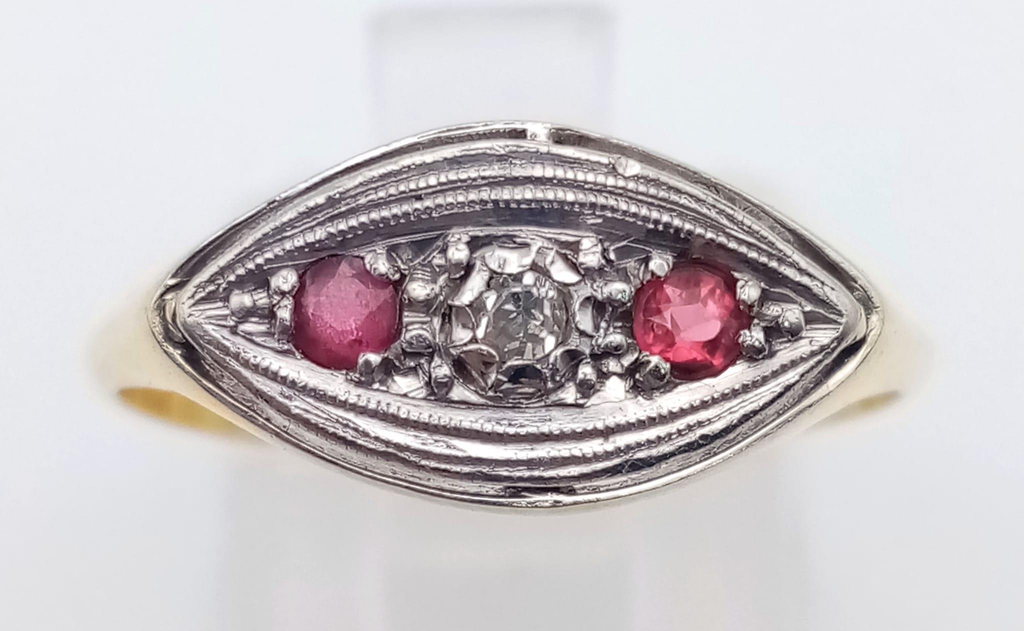 A vintage 18K yellow gold and platinum ring with a single diamond and two rubies. Ring size: R,