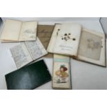 An early 20th century scrapbook, filled with various pressed flowers and foliage, a sketch book, and