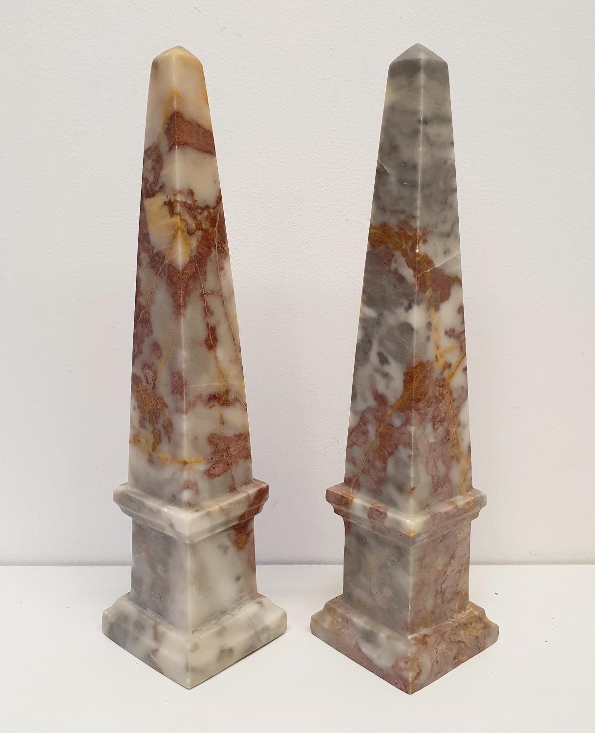 A pair of pink marble obelisks, 33 cm high, and a pair of wooden stands (4)