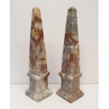A pair of pink marble obelisks, 33 cm high, and a pair of wooden stands (4)