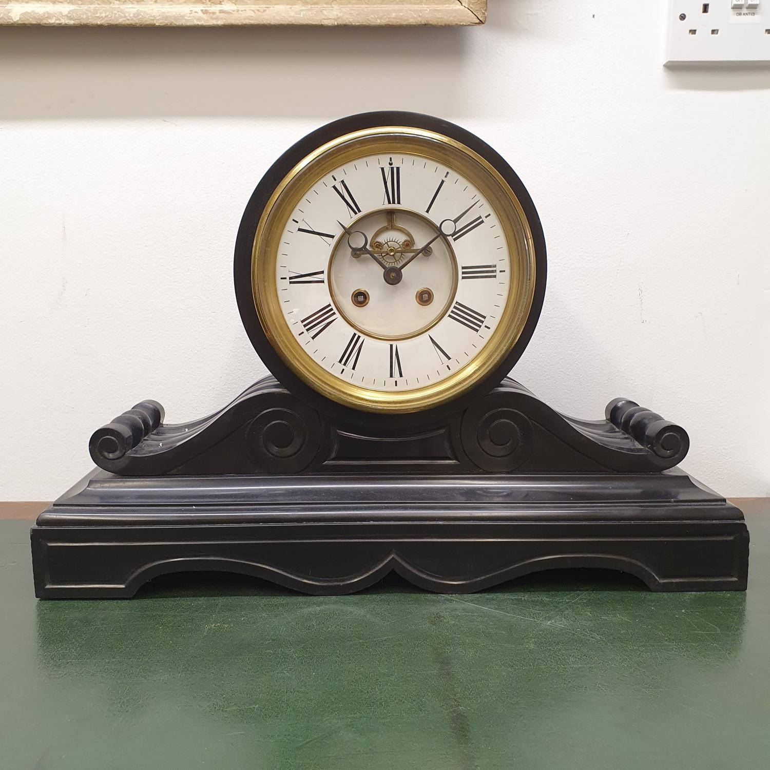 A mantel clock, with Roman numerals and a visible anchor escapement, in a polished slate case, 57 cm