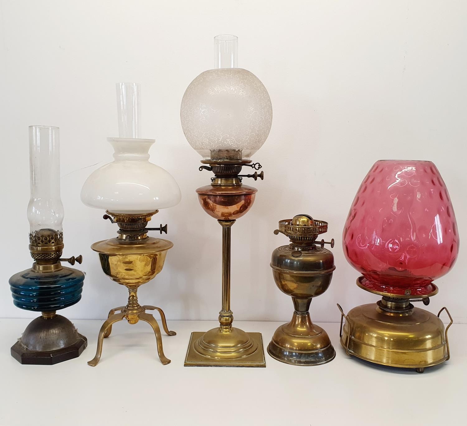 A brass oil lamp base, four others similar, three glass shades and three glass chimneys (2 boxes)