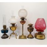 A brass oil lamp base, four others similar, three glass shades and three glass chimneys (2 boxes)