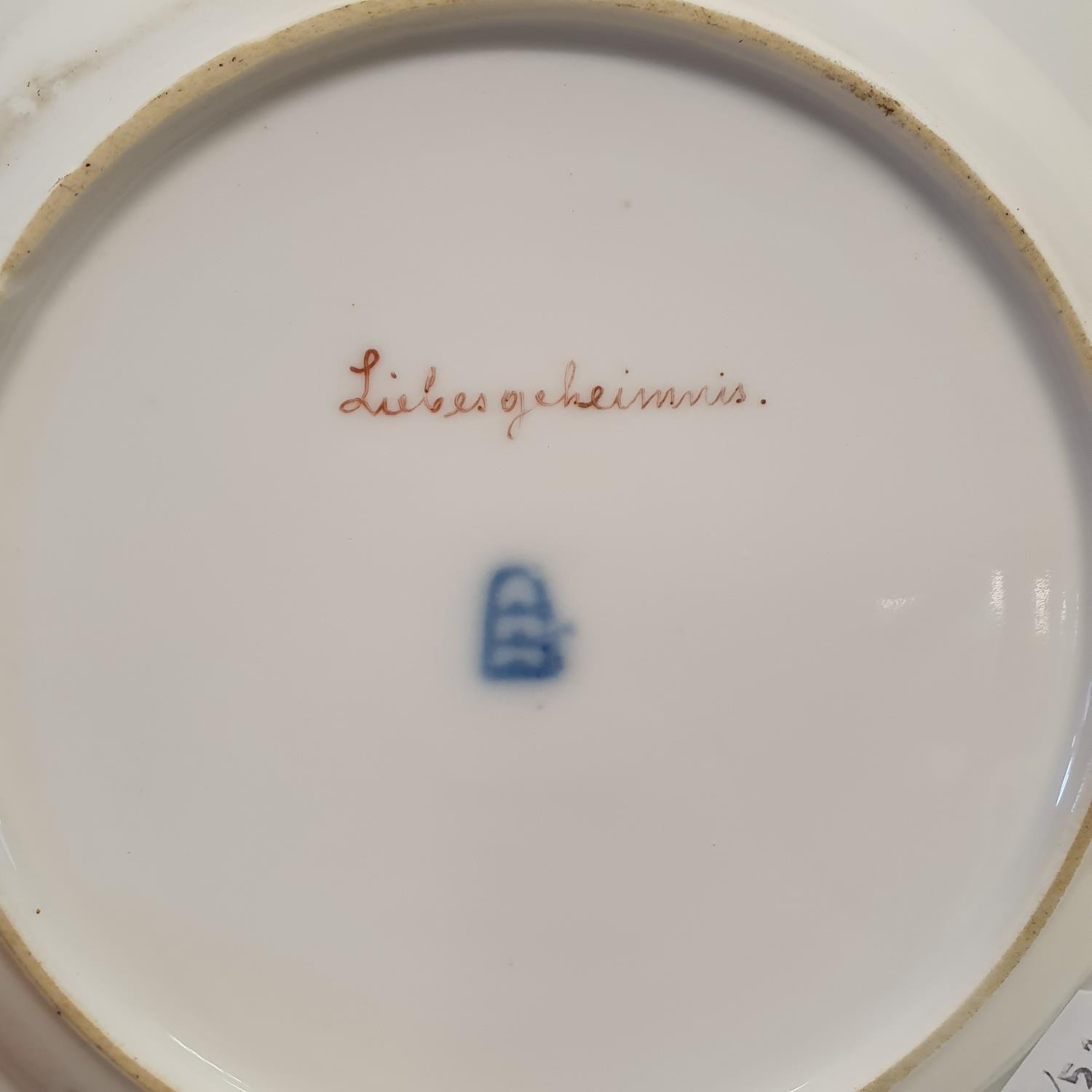 A Vienna porcelain plate, Liebesgeheimnis, within a blue and gilt border, 21 cm diameter Gilt a - Image 2 of 2