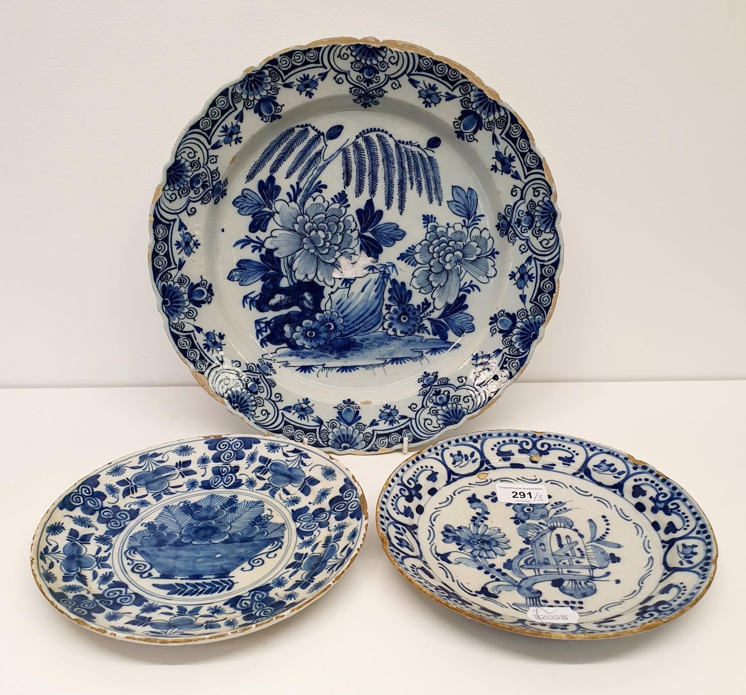 A 19th century Delft plate, 34 cm diameter, and two plates, 23 cm diameter (3) All with various