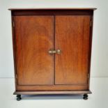 A walnut table top two door cabinet, on turned feet, 31 cm wide