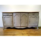 A French oak serpentine sideboard, with a painted front, having two cupboard doors, flanked by two