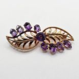 A yellow coloured metal and amethyst floral brooch