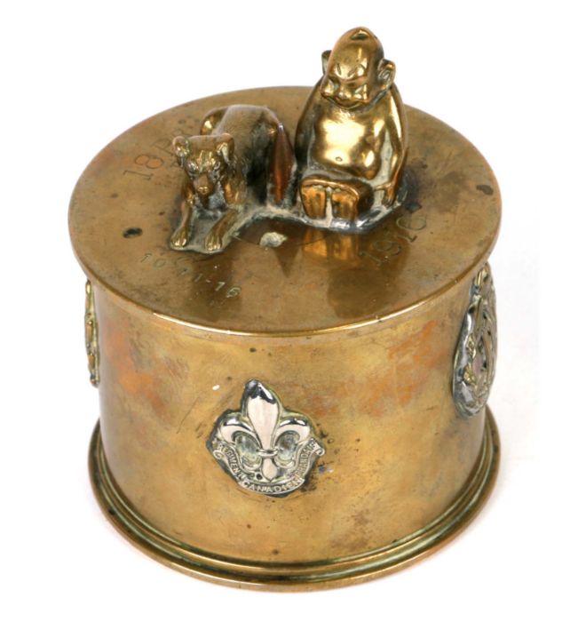 A WWI trench art tobacco jar and over with applied cap badges including RF, American North West