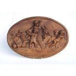 A large oval carved walnut plaque depicting cherubs with a goat, 63cms wide.