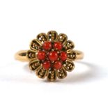 A yellow metal dress ring set with seven coral cabochons, approx UK size 'M', 4.1g.