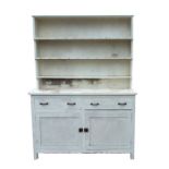 An early 20th century painted pine dresser with three-tier plate rack above two frieze drawers and