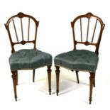 A pair of late Victorian walnut parlour chairs with overstuffed seats and tapering ring turned front