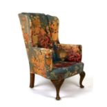 A country house George style upholstered wing back armchair with carved shell capped cabriole