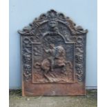 A cast iron fireback decorated in relief a figure on horseback. 56cm wide together with a large iron