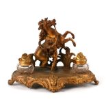 A 19th century gilt metal pen & ink stand in the rococo taste surmounted a horse and attendant,