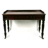 A 19th century mahogany writing table with three frieze drawers, on reeded turned legs terminating