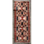 A Persian Tabriz hand knotted woollen runner with geometric design on a red ground, 295 by 75cms (