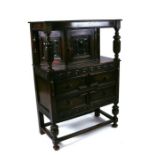 A 17th century style oak court cupboard of small proportions having a cupboard with three carved
