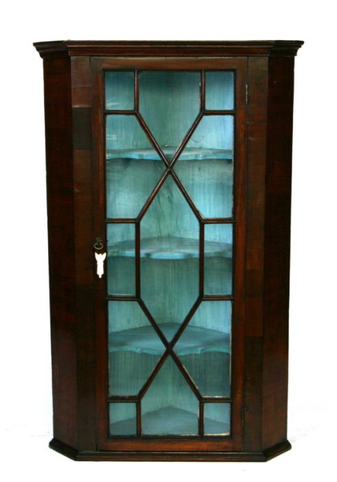 A 19th century mahogany corner cupboard with astragal glazed door enclosing a shelved interior,