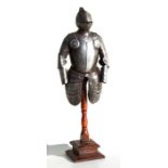 A tin plate miniature suit of armour mounted on a wooden stand 55cms (21.625ins) high