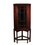 A mahogany corner display cabinet on stand, the glazed door enclosing a shelved interior, 65cms