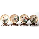 A set of four Chinese shells, each individually decorated with exotic birds and flowers, on hardwood