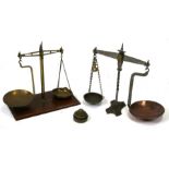 A set of brass balance scales on a mahogany base; together with a set of steel balance scales, the