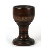 A turned treen oak goblet of baluster form, the name 'Elizabeth' inset in white metal pieces,