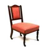 An Edwardian mahogany nursing chair with upholstered back and seats, on turned front legs.