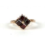A 9ct gold ring set with four square cut garnets, approx UK size 'P'.