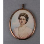 An oval portrait miniature depicting a young lady in a high necked white dress, mounted in a gilt