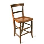 A 19th century beech correction chair with caned seat.