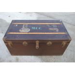 A large travel trunk with wooden strapping and metal corners and various shipping line luggage