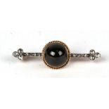 A Victorian gold and platinum bar brooch with central garnet cabochon flanked by rose cut